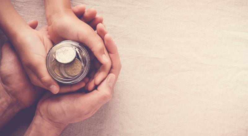 Padre sostiene mano de hijo con monedas