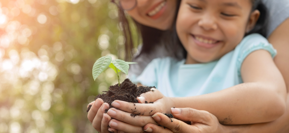 Mamá cuida medio ambiente plantando con su hija