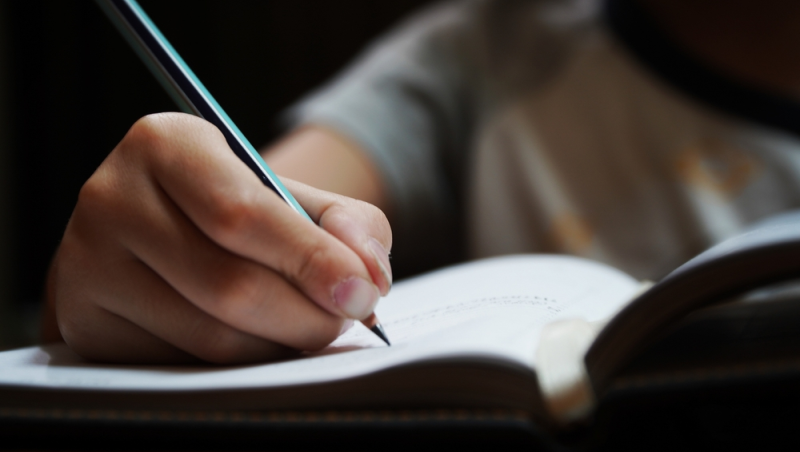 Niño de primaria realiza ejercicios de ortografía en cuaderno