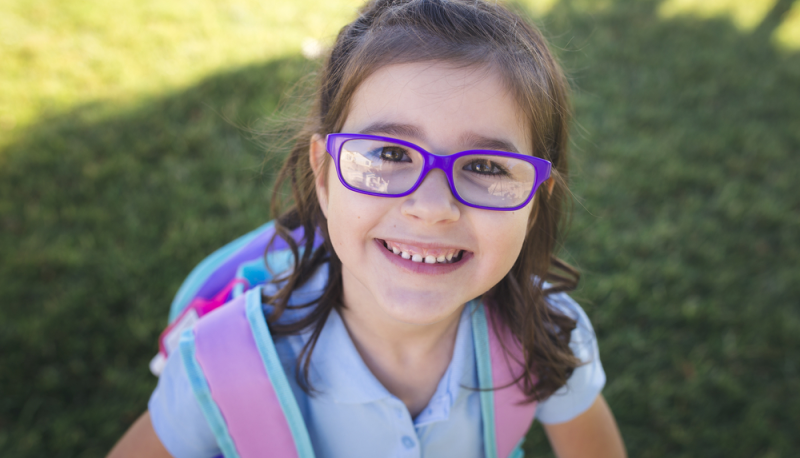 Niña de preescolar con lentes en espacio verde