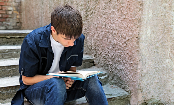 Estudiante de secundaria haciendo lectura sentado en escalones