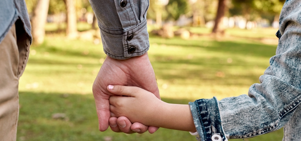 Padre toma de la mano a su hijo de primaria