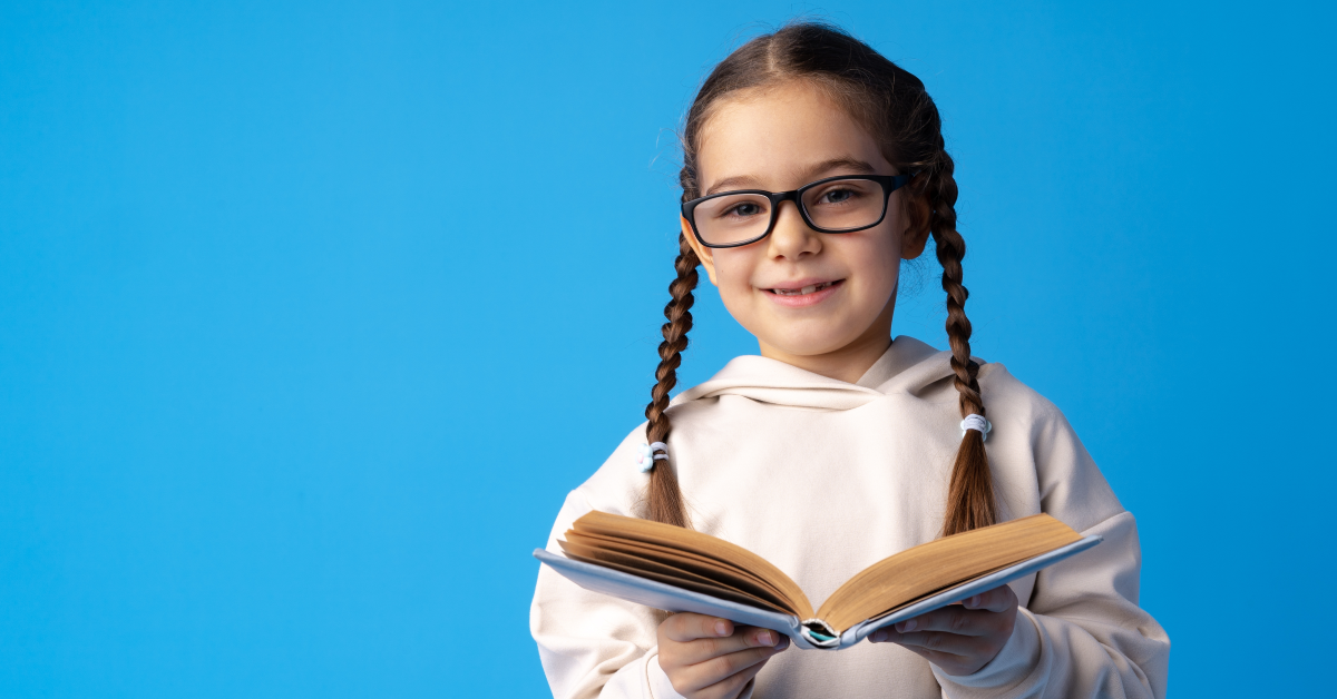 Niña de primaria con libro abierto que lee