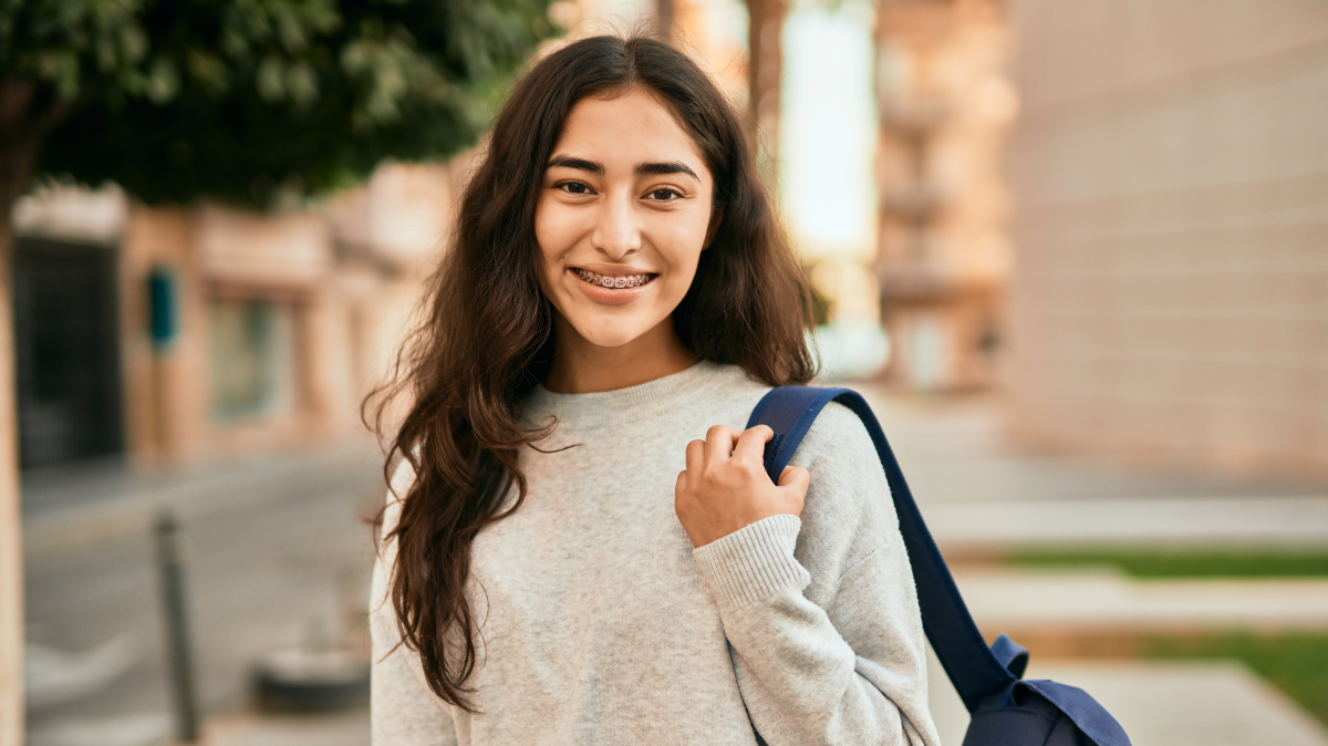 Niña de secundaria sonriente afuera de su escuela